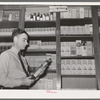Druggist in front of patent medicine shelf. San Augustine, Texas