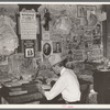 Small grocery store owner surrounded by bills. San Augustine, Texas