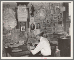 Small grocery store owner surrounded by bills. San Augustine, Texas