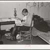Boy reading in bedroom. Note lack of proper bed clothing. Home of A.O. Ryland near Williston, North Dakota