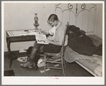 Boy reading in bedroom. Note lack of proper bed clothing. Home of A.O. Ryland near Williston, North Dakota
