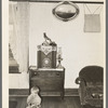 One of the Bakke children in living room of farm house. Note decorations and chair. Near Ambrose, North Dakota