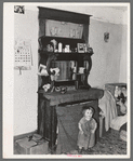 Baby in front of dresser in John Baker's farm home, Divide County, North Dakota