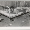 Boy resting on bed in attic of sharecropper shack, New Madrid County, Missouri