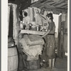Woman living in shack at Tin Town, Caruthersville, Missouri, in front of shelf used as kitchen cabinet. Note ceiling and dirt floor