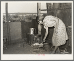 Girl tending fire in shack home. Tin Town, Caruthersville, Missouri