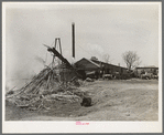 Sawmill and waste lumber pile being burned. Wells, Texas