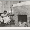 Wife of FSA (Farm Security Administration) client sewing in front of fireplace in her home on Sabine Farms. Marshall, Texas