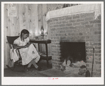 Wife of FSA (Farm Security Administration) client sewing in front of fireplace in her home on Sabine Farms. Marshall, Texas