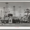 Derricks in residential section of Kilgore, Texas. Notice church