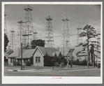 Derricks in residential section of Kilgore, Texas. Notice church