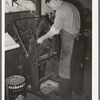 Placing pieces of leather into crimping machine to shape the lowers of the boots. Boot shop, Alpine, Texas