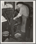 Placing pieces of leather into crimping machine to shape the lowers of the boots. Boot shop, Alpine, Texas