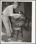 Applying pressure by means of sandbags to glued leather in saddle repairing shop. Alpine, Texas