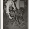 Removing excess moisture from leather by means of rollers. Leather must be moistened and tempered before being used and then excess liquid is pressed out. Bootmaking shop, Alpine Texas