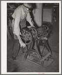 Removing excess moisture from leather by means of rollers. Leather must be moistened and tempered before being used and then excess liquid is pressed out. Bootmaking shop, Alpine Texas