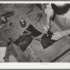 Tamping glued leather together after the heel section of uppers has been attached to stitched section of boot. Bootmaking shop, Alpine, Texas