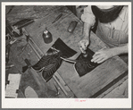 Tamping glued leather together after the heel section of uppers has been attached to stitched section of boot. Bootmaking shop, Alpine, Texas