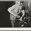 Applying cement for gluing leather of saddle to the base before sewing. Saddle shop, Alpine, Texas