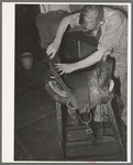 Workman repairing saddle. Alpine, Texas, saddle shop