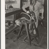 Saddle maker applying cement to glue parts of saddle together. Saddle shop, Alpine, Texas