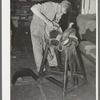 Saddle maker tamping leather in place after cementing it. Saddle shop, Alpine, Texas
