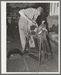 Saddle maker tamping leather in place after cementing it. Saddle shop, Alpine, Texas
