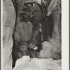 Mexican cowboy holding front leg of calf during branding. Cattle ranch near Marfa, Texas