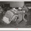 Action in loading a bale of cotton onto truck for transporting to compress. Houston, Texas