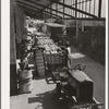 Unloading bales of cotton from truck-drawn trailers at compress, Houston Texas. Cotton was transported to the compress from Oklahoma in large trucks in background