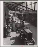 Unloading bales of cotton from truck-drawn trailers at compress, Houston Texas. Cotton was transported to the compress from Oklahoma in large trucks in background