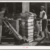 Putting bale of cotton onto hand truck. Compress, Houston, Texas