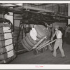 Removing bale of cotton from conveyer. Compress, Houston, Texas