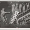 Shoving a bale of cotton onto conveyor at compress. Houston, Texas