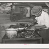 Man slicing barbecue at lunch stand at the Gonzales County Fair. Gonzales, Texas