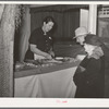 Farm couple watching the saleswoman demonstrate the use of a gadget at booth at the Gonzales Country Fair, Texas