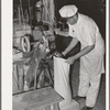 Proprietor of feed mill filling sack with freshly-ground corn meal. Taylor, Texas