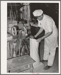 Proprietor of feed mill filling sack with freshly-ground corn meal. Taylor, Texas