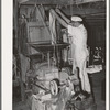 Proprietor of feed mill emptying sack of shelled corn into hopper for grinding into cornmeal. Taylor, Texas