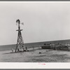 Windmill and watering trough on large farm near Ralls, Texas. Wife of day laborer is drawing water