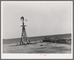 Windmill and watering trough on large farm near Ralls, Texas. Wife of day laborer is drawing water