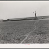 Windmill and hog pen and shed on large 4900 acre farm near Ralls, Texas. Path leads through fields from day laborers' homes