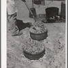 Piling coals on top of Dutch oven to bake bread. Ranch near Spur, Texas