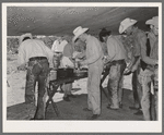 Cowboys of the SMS Ranch serving themselves at dinner at chuck wagon. Ranch near Spur, Texas