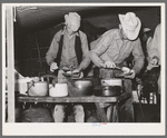 Cowboys of the SMS Ranch serving themselves at dinner at chuck wagon. Ranch near Spur, Texas
