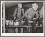 Cowboys of the SMS Ranch serving themselves at dinner at chuck wagon. Ranch near Spur, Texas