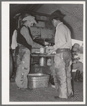 Cowboys of the SMS Ranch serving themselves at dinner at chuck wagon. Ranch near Spur, Texas
