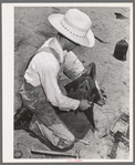 Day laborer adjusting plow point on tractor. Large farm near Ralls, Texas