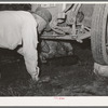 Migrant steeple-jack removing the crank case from his automobile. Near Prague, Oklahoma. When he secures a job, the entire family, consisting of his father and mother, wife and sister, all help with the painting