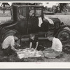 Migrant workers eating dinner by the side of their car while they are camped near Prague, Oklahoma